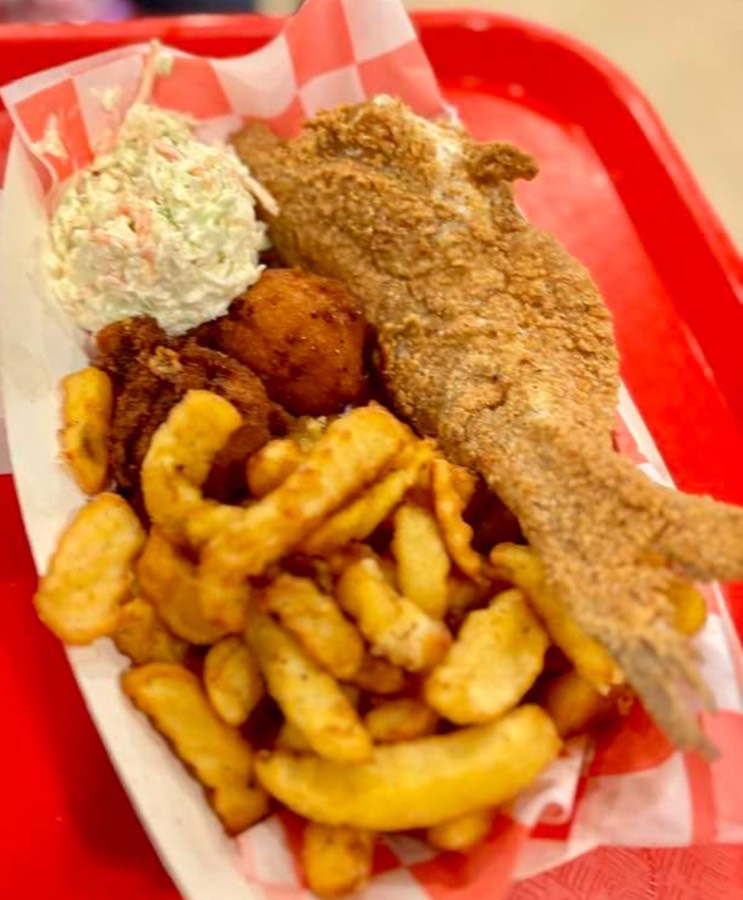 Whole fried catfish basket with fries, hushpuppies, and slaw